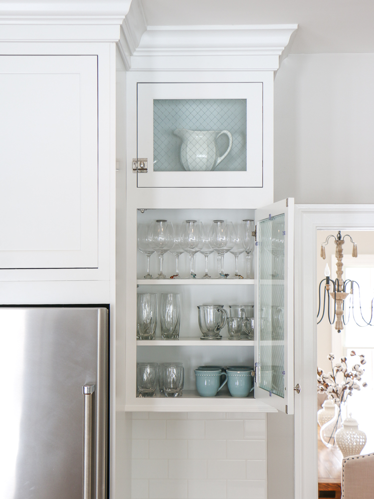 White kitchen cabinet with glass front doors, glass and cup storage