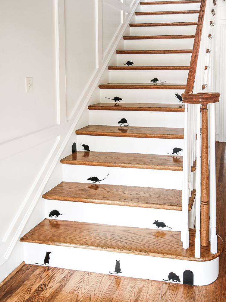 stairway with hardwood floors and white walls with molding, black mouse decals staggered on stair risers