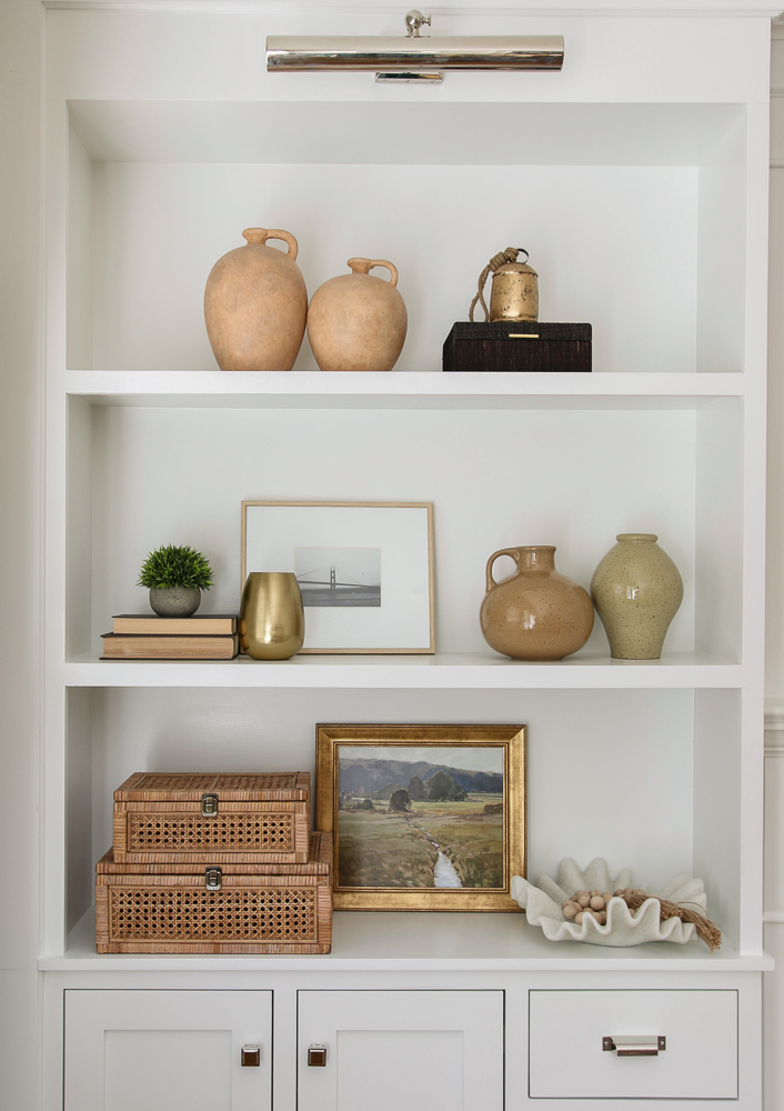Open builtin shelves expertly styled with decorative objects, boxes, vases, artwork