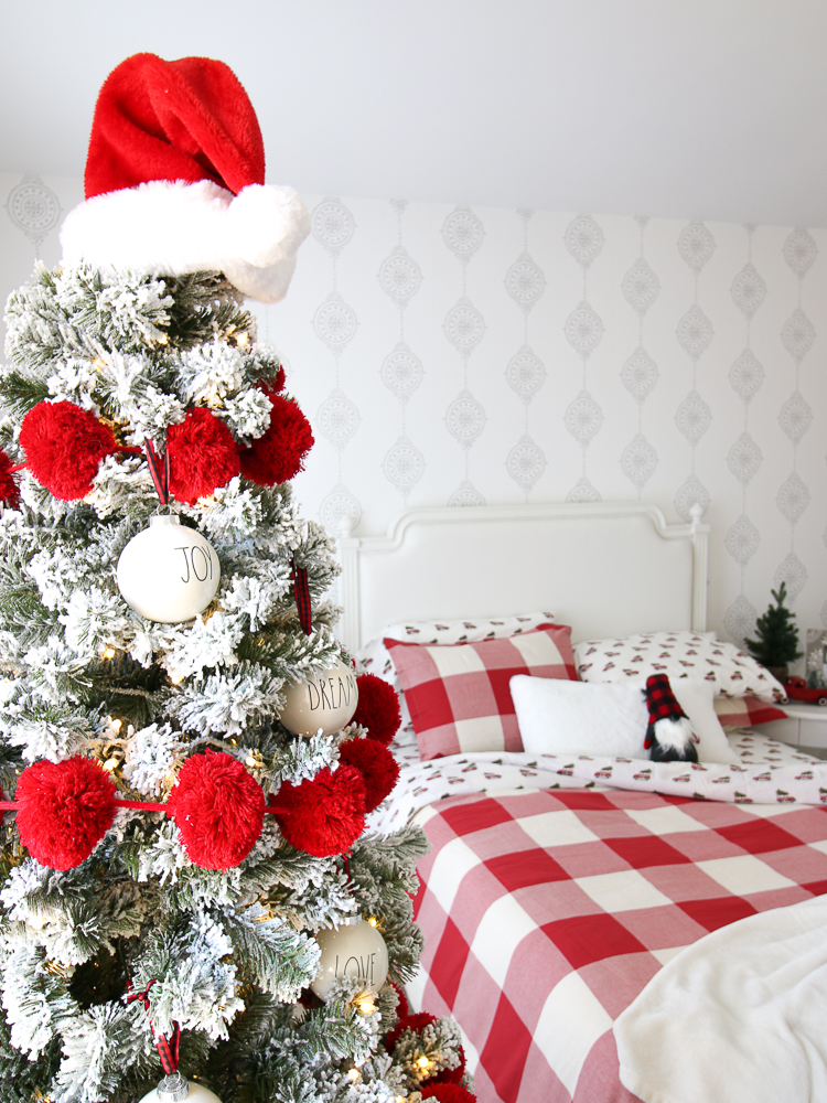 girl's bedroom decorated for Christmas with red and white bedding, flocked tree, red pom-pom garland