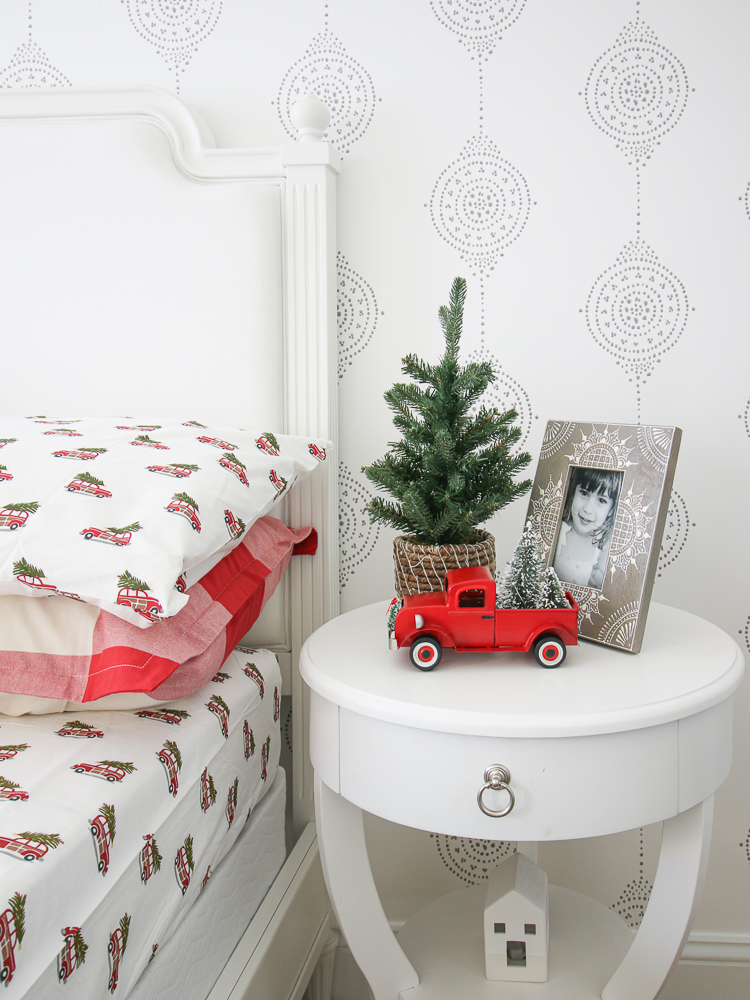 Girls bedroom decorated for Christmas, mini tree and vintage red truck on white nightstand, Pottery Barn kids Christmas sheets and comforter