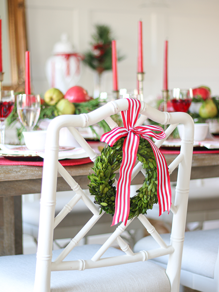 Preserved mini boxwood wreath hanging on the back of white Chippendale chair, Christmas tablescape with traditional red theme, green and gold accents
