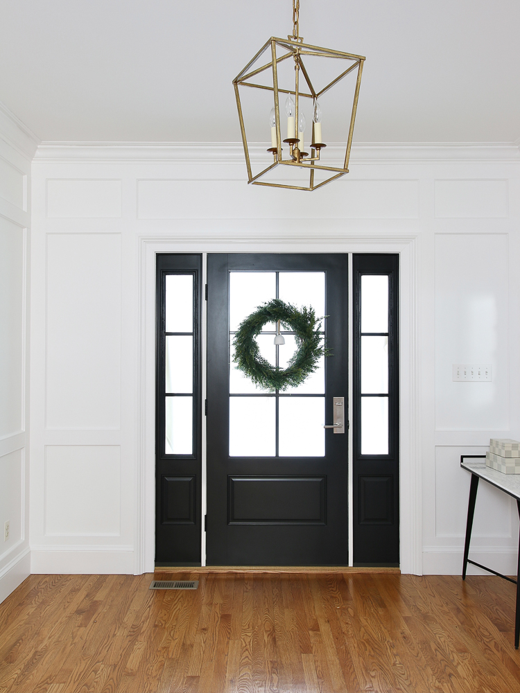 entry painted ultra pure white with wall molding, black front door with window, wreath on door, small entry table, hardwood floors