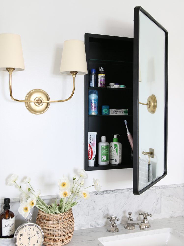 marble bathroom design, black vanity mirror with hidden medicine cabinet, polished nickel faucet, brass sconces