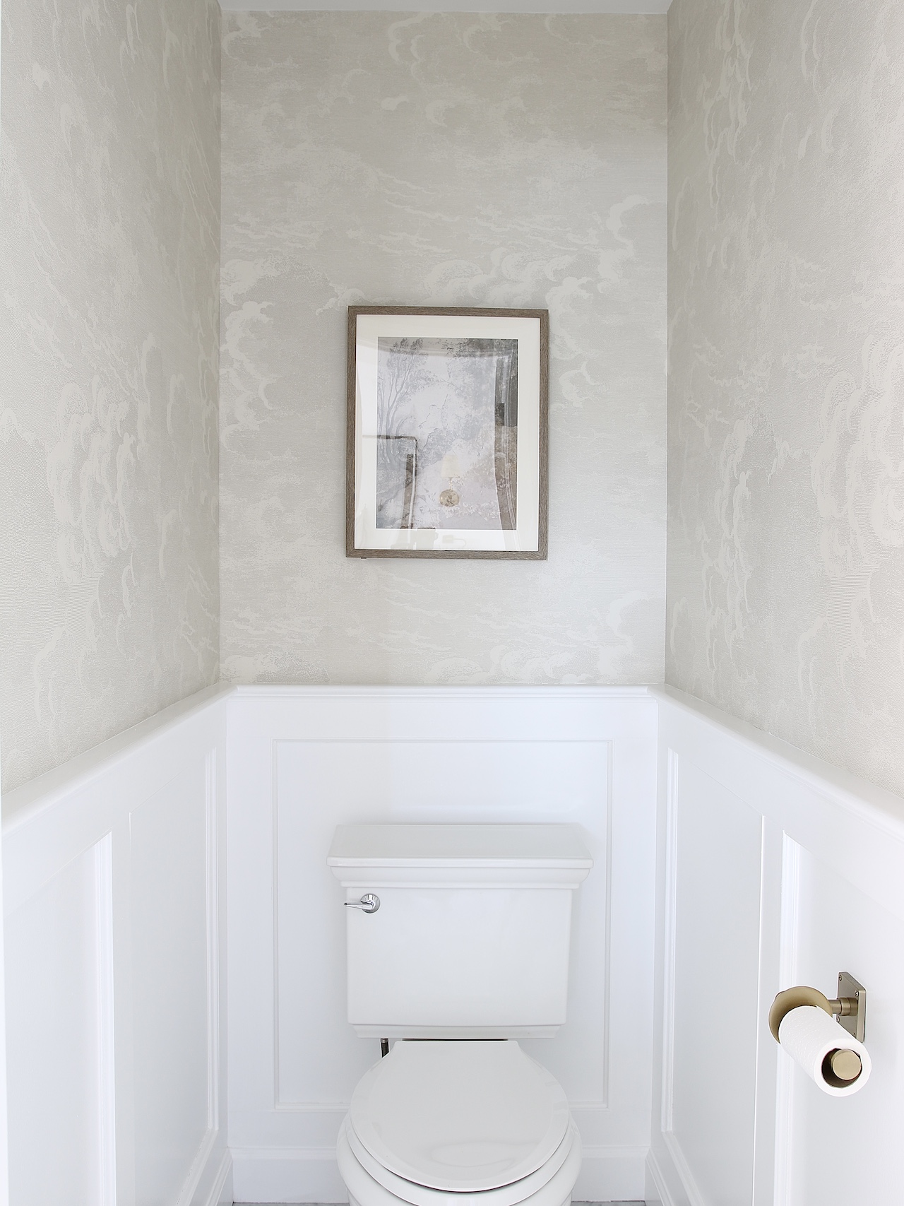 toilet room with nuvelette wallpaper on top and white molding on bottom of walls, brass toilet paper holder
