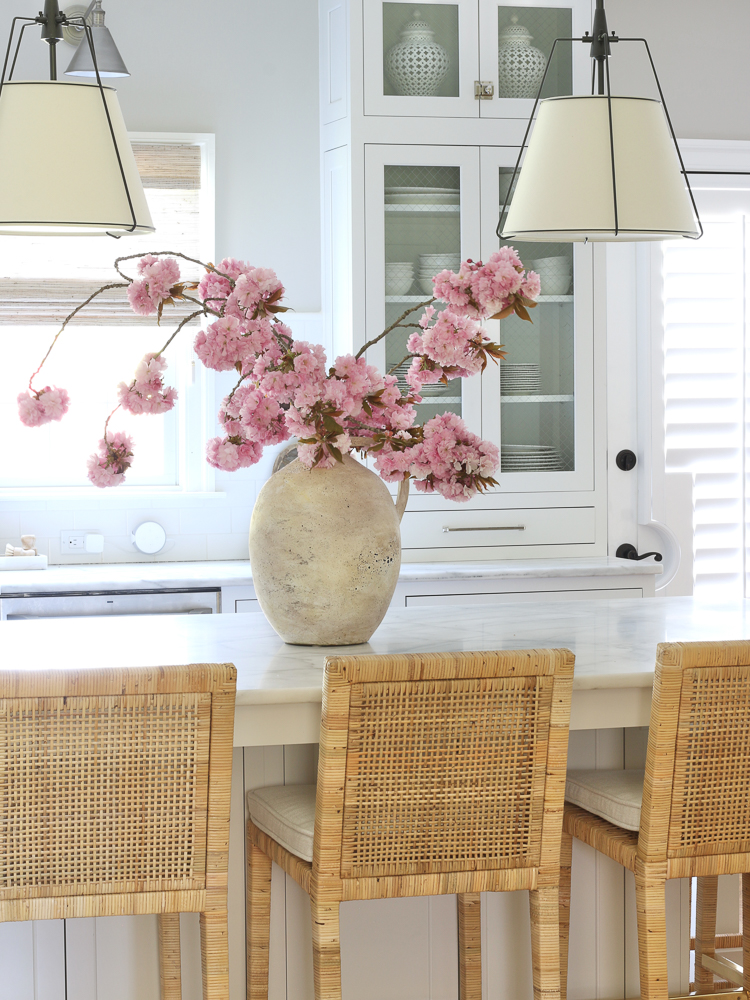 cherry blossom branches in ceramic vase, rattan counter stools, cone shade pendant, kitchen decor