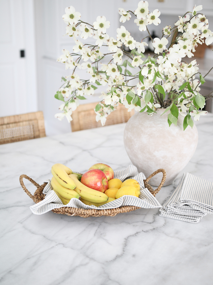 marble kitchen counter, woven tray with fruit, artisan vase