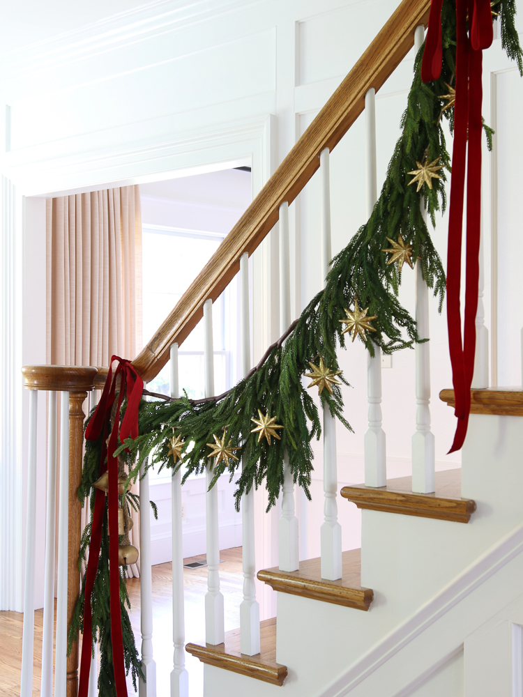 realistic garland for Christmas decorating of staircase banister, red ribbons and gold stars draped in garland