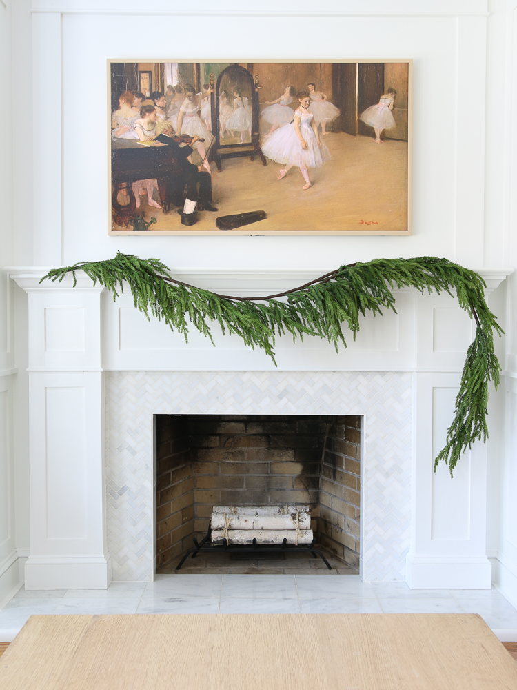 fireplace mantel with one or two faux Norfolk pine garlands, frame TV with vintage art, marble fireplace surround