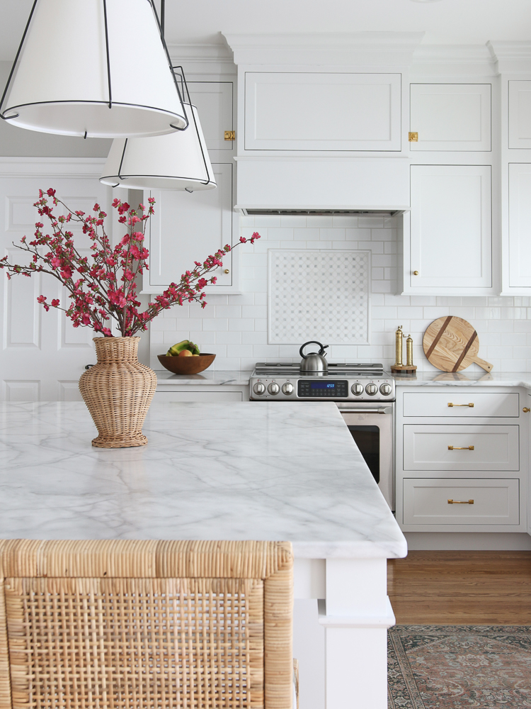 honed marble countertops with white kitchen cabinets, white subway tile backsplash