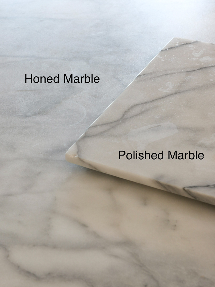 polished marble serving board on top of honed marble countertops