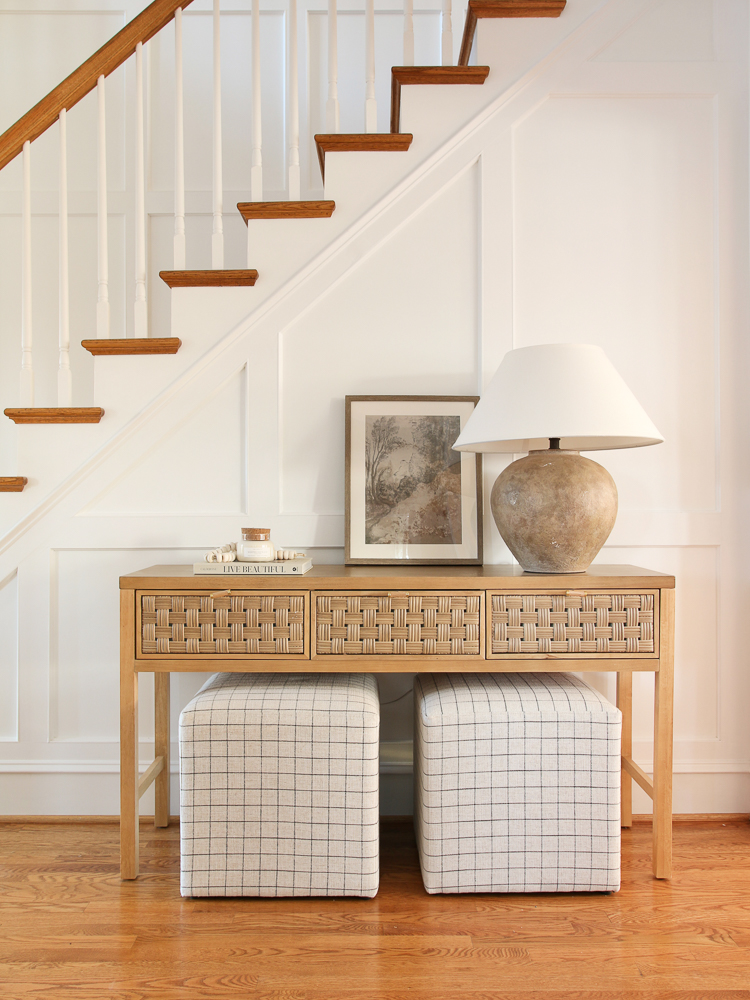 Stairway molding area with console table, ottomans, lamp