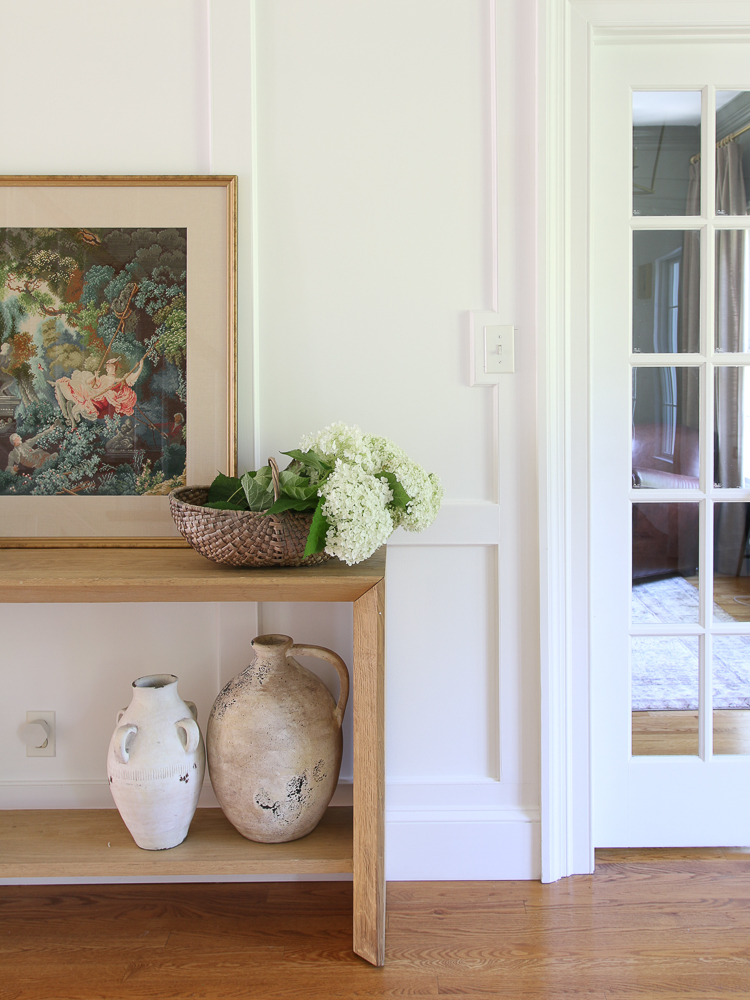 Console table with ceramic vases and wall art, flower basket