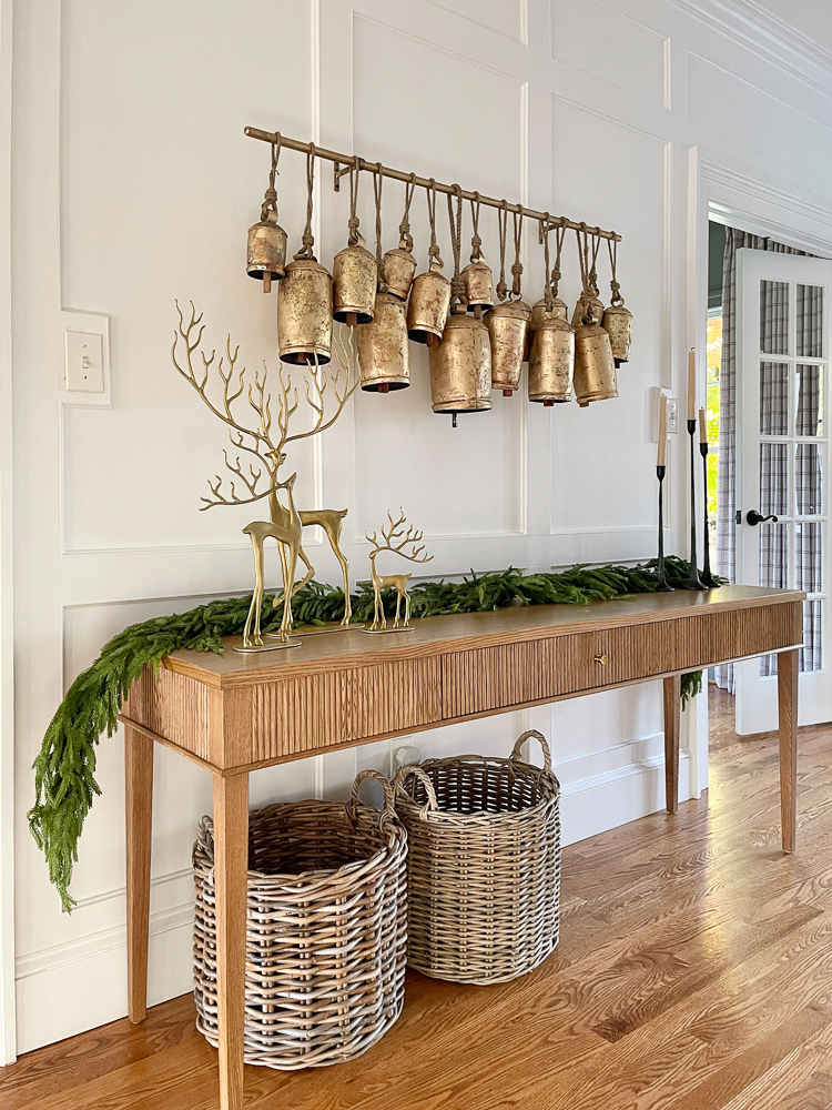 white oak fluted console table, woven baskets, brass reindeer objects, brass bells, garland