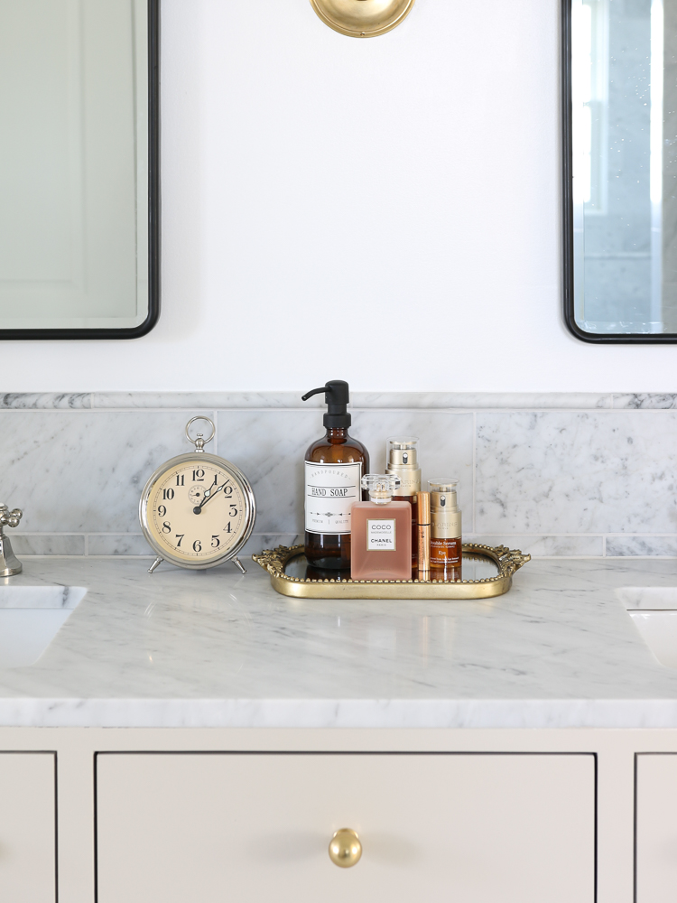 clutter free bathroom vanity countertop with soap dispenser and perfumes on decorative mirrored tray