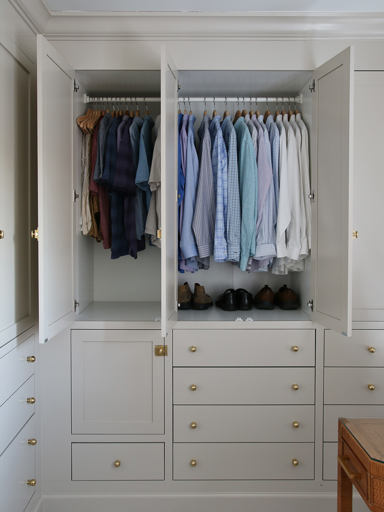 open cabinet doors showing clothes organized on wooden hangers