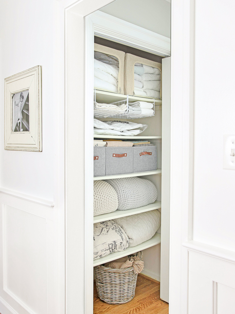 full length view of hallway linen closet organization, neutral bins and linens