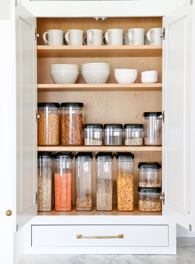 open pantry cabinet doors showing organized snacks and cereals in clear plastic containers