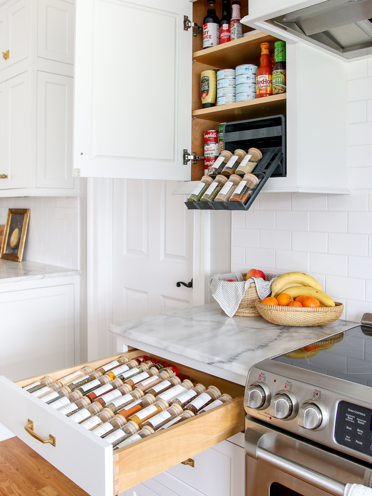 white kitchen, pantry cabinet and drawer next to stove open showing organized spices , baskets with fruit on countertop