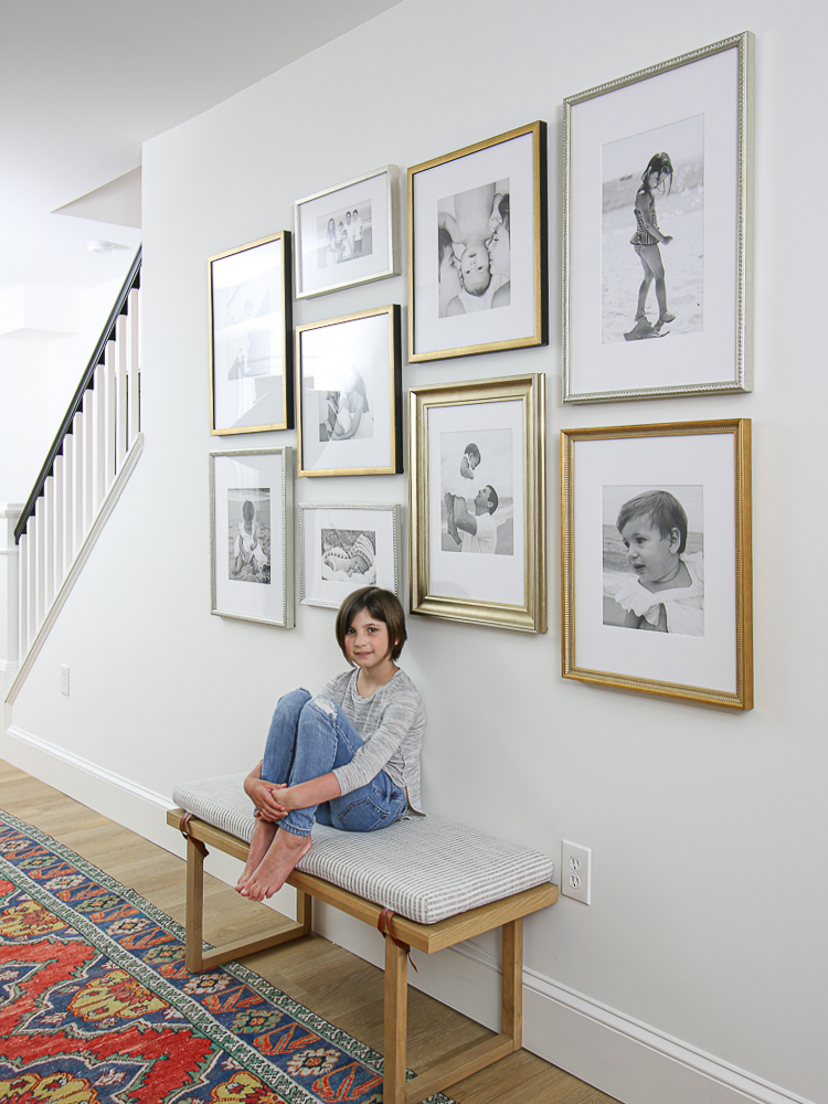 white wall with gallery frames and child sitting on bench