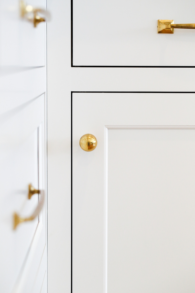 close up of brass cabinet hardware, knobs and pulls, white kitchen