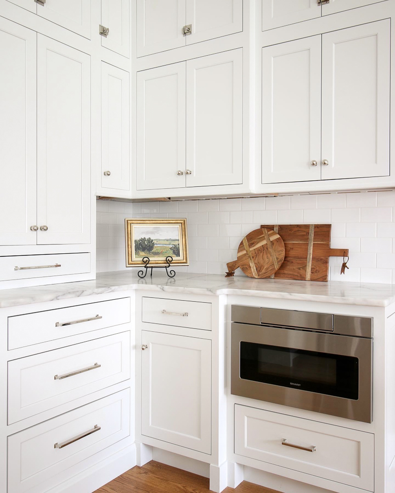 corner of classic white kitchen with polished nickel hardware on cabinets and drawers