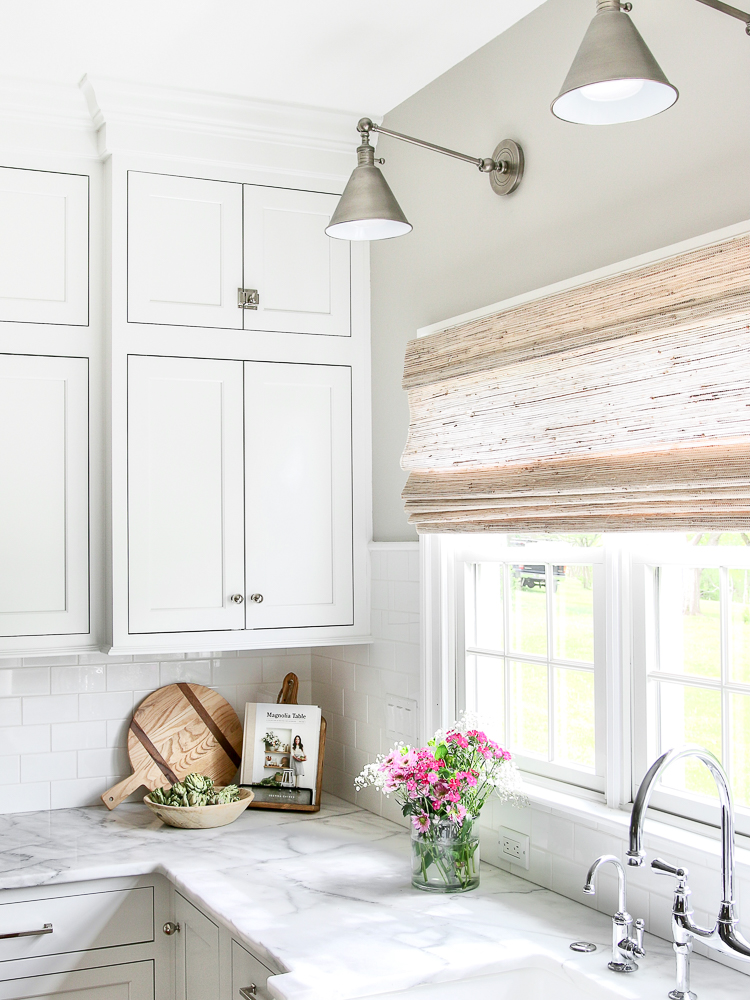 view of classic white kitchen with woven shade on window above sink