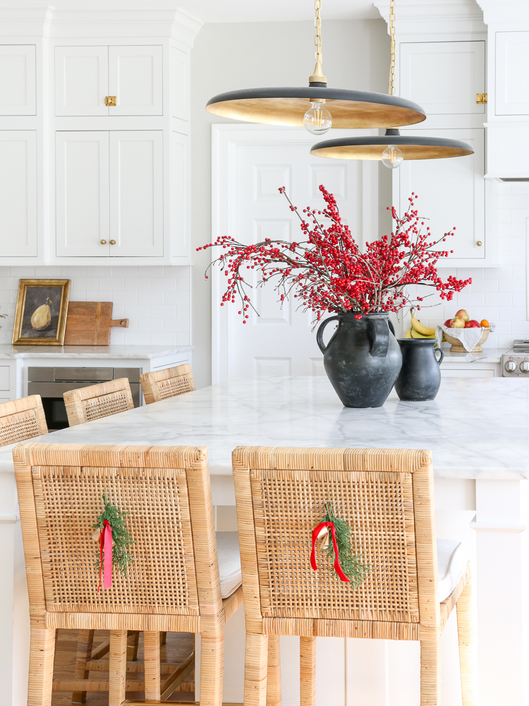 classic white kitchen with Christmas decor on countertop and on back of counter stools, greenery and winter stems 