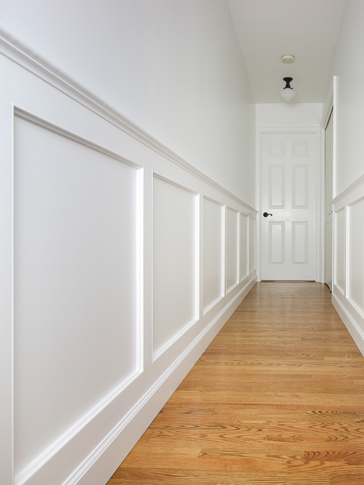 white hallway walls with molding and hardwood floors to update a cookie cutter home