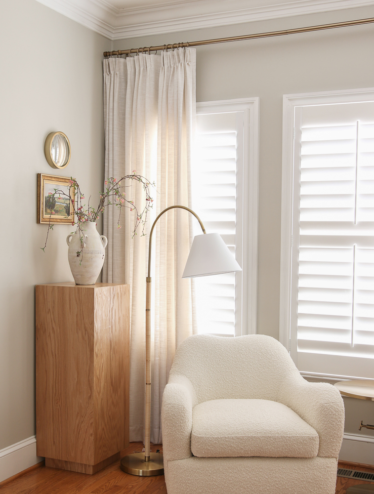 Living room view with linen drapes layered over white interior shutters for a custom look 