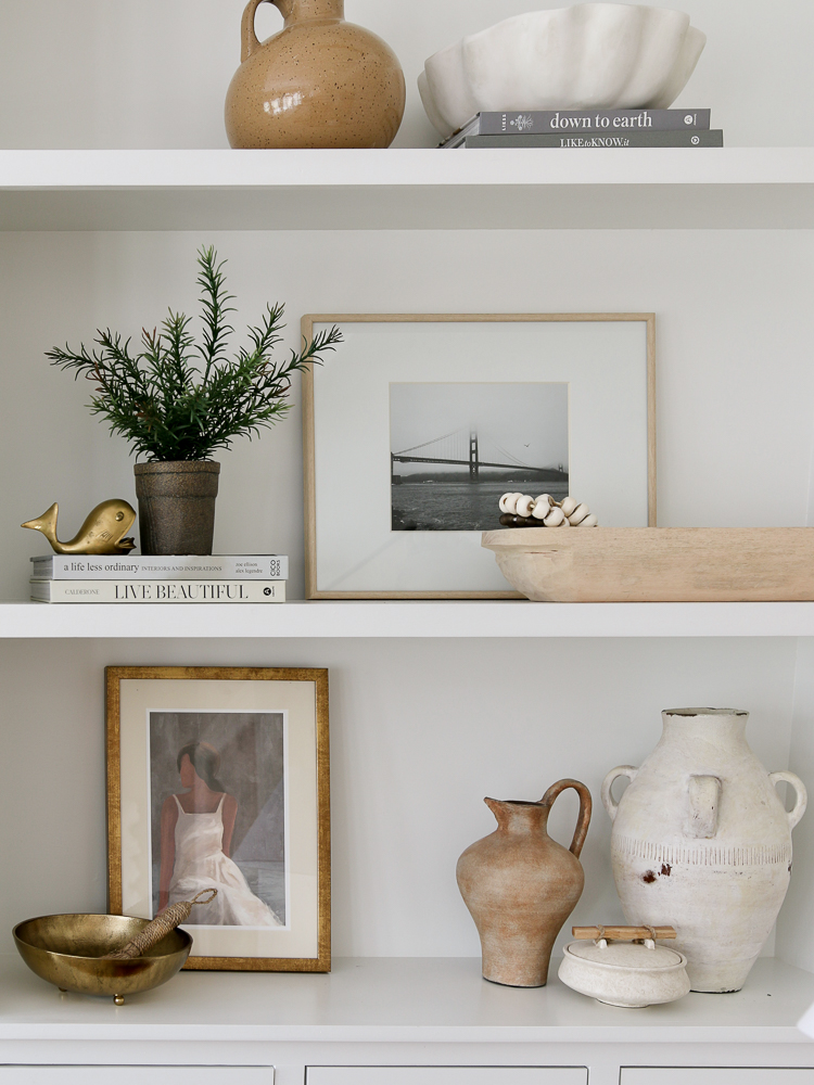 builtin shelves with wooden, brass, and pottery decor