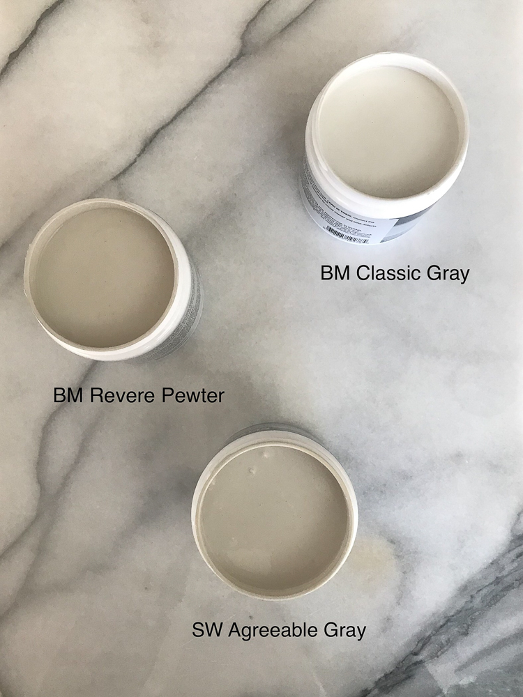 assortment of gray paint sample containers open on marble countertop