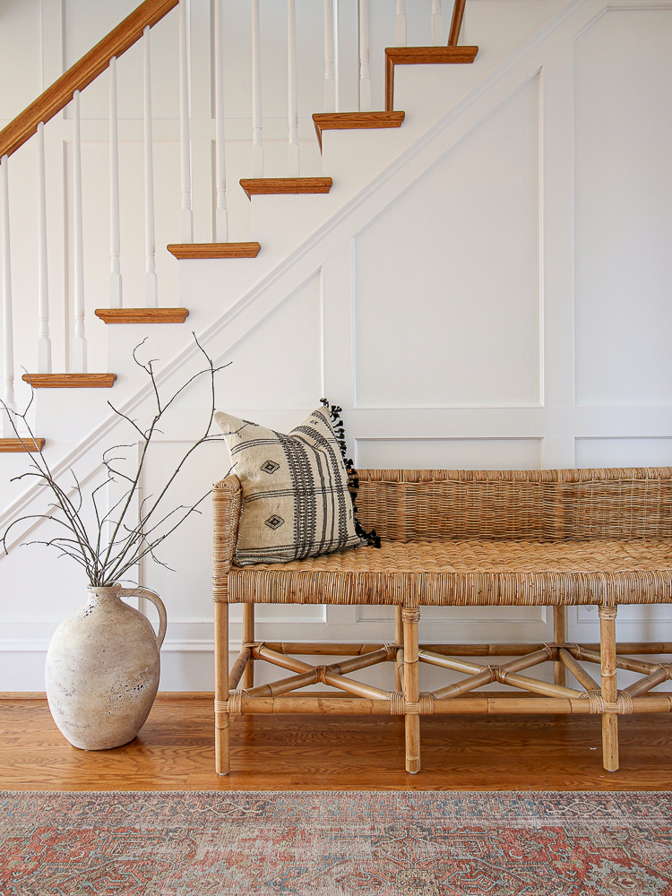 view of white stairway wall with molding, styled with Serena and lily bench and vase with branches