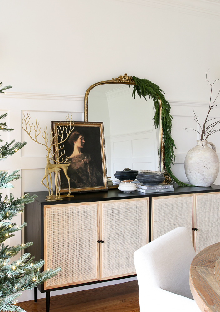 3 ft Anthropologie mirror with garland styled on a black and woven sideboard
