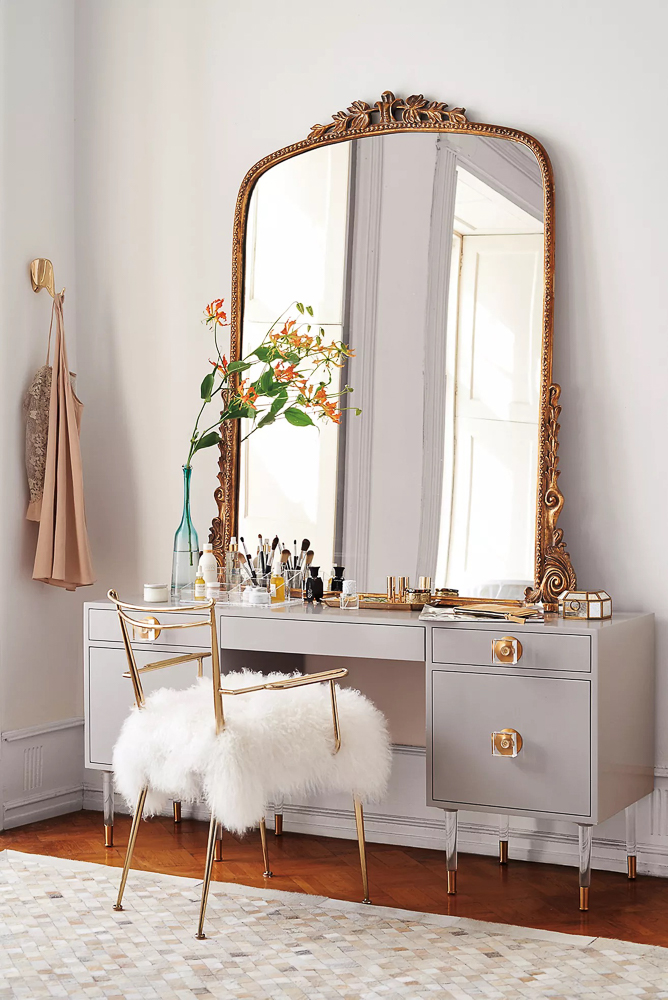large gleaming primrose mirror styled on a vanity table, glamorous details in chair and knobs on gray vanity