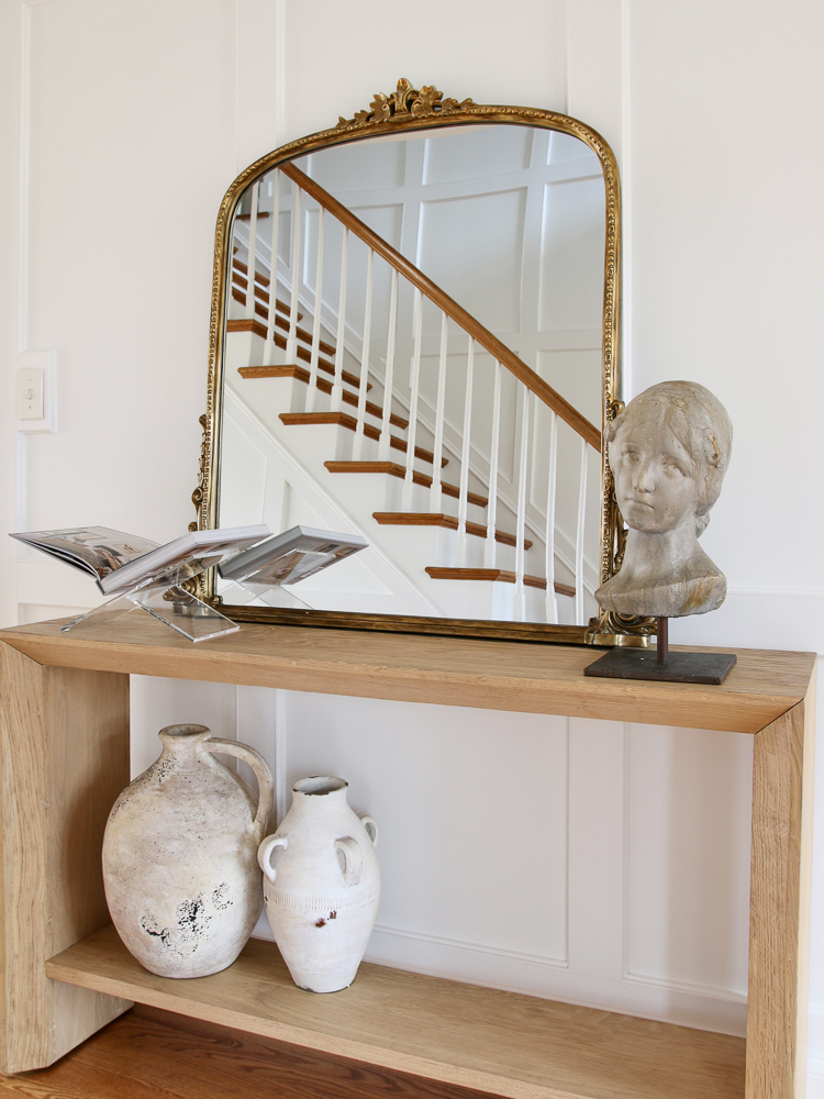 entryway console table with 3 ft Anthropologie mirror, styled with an open book on an acrylic stand and a large bust