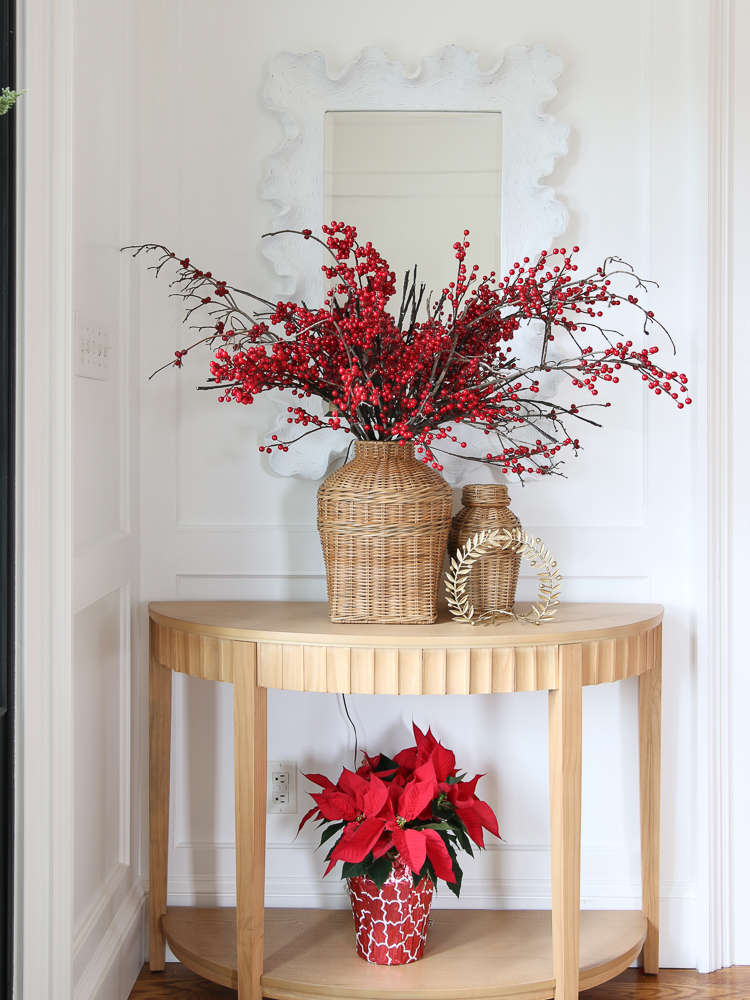 wicker jars on entry console table with stems and red berries