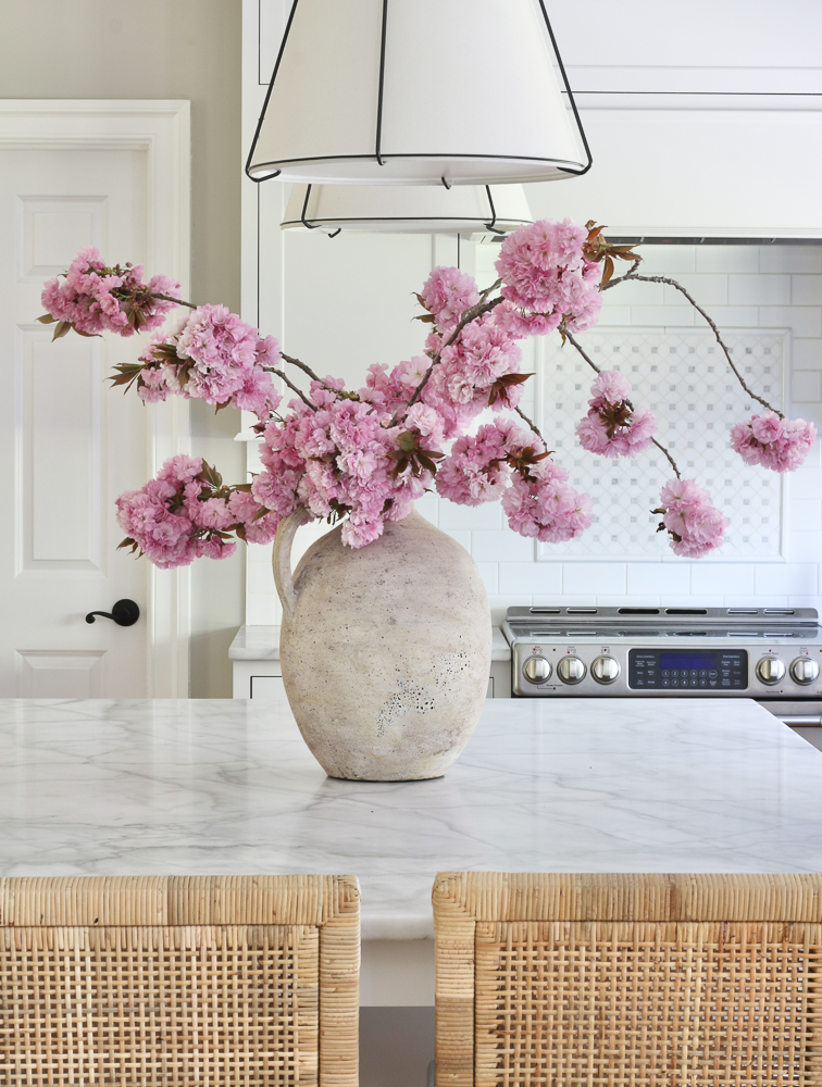 vase with fresh cut cherry blossom stems on kitchen counter