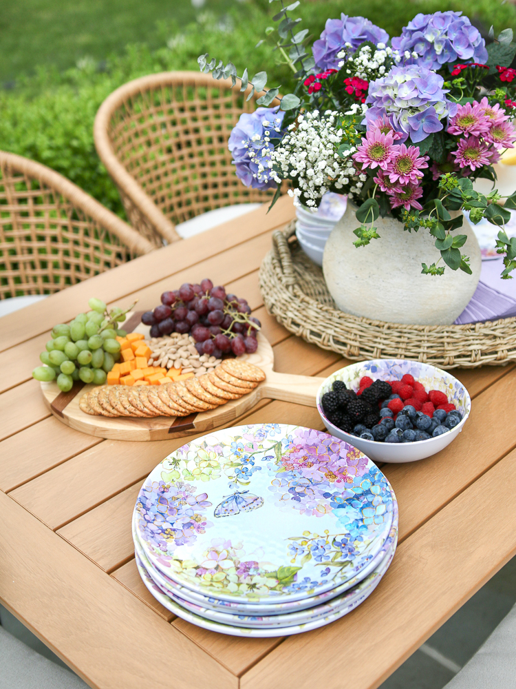 outdoor tablescape with a fresh floral arrangement and charcuterie board ready to welcome guests
