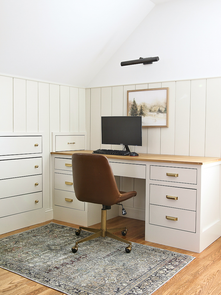 bedroom corner with built-in drawers, custom desk with aged brass pulls, vertical shiplap on walls