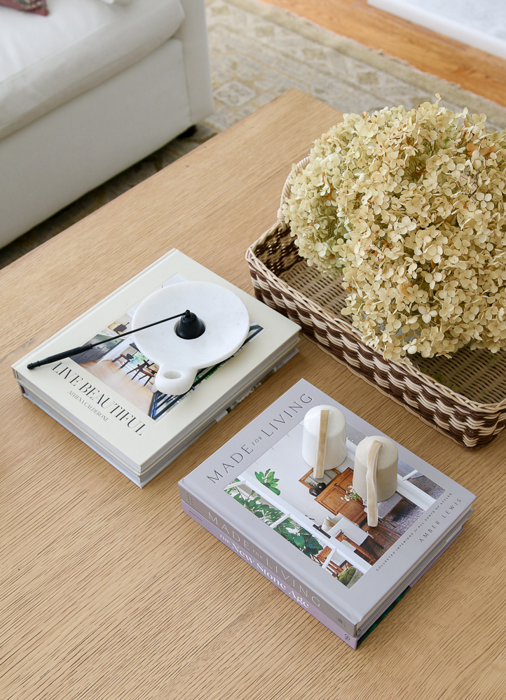 overhead view of home decor gifts on a coffee table including home decor books, an candle snuffer, and dried hydrangeas