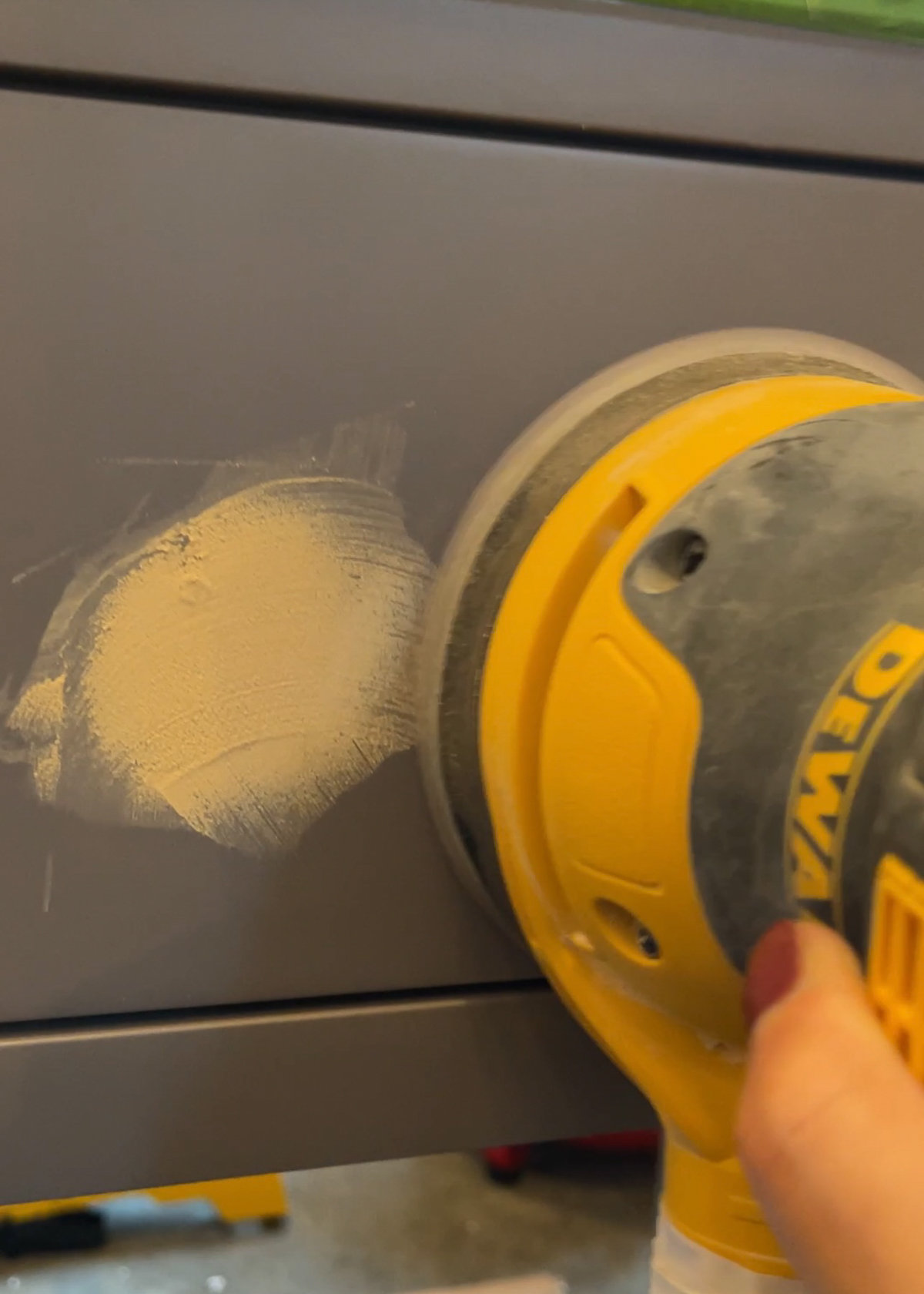 orbital sander sanding wood filled hardware hole on cabinet