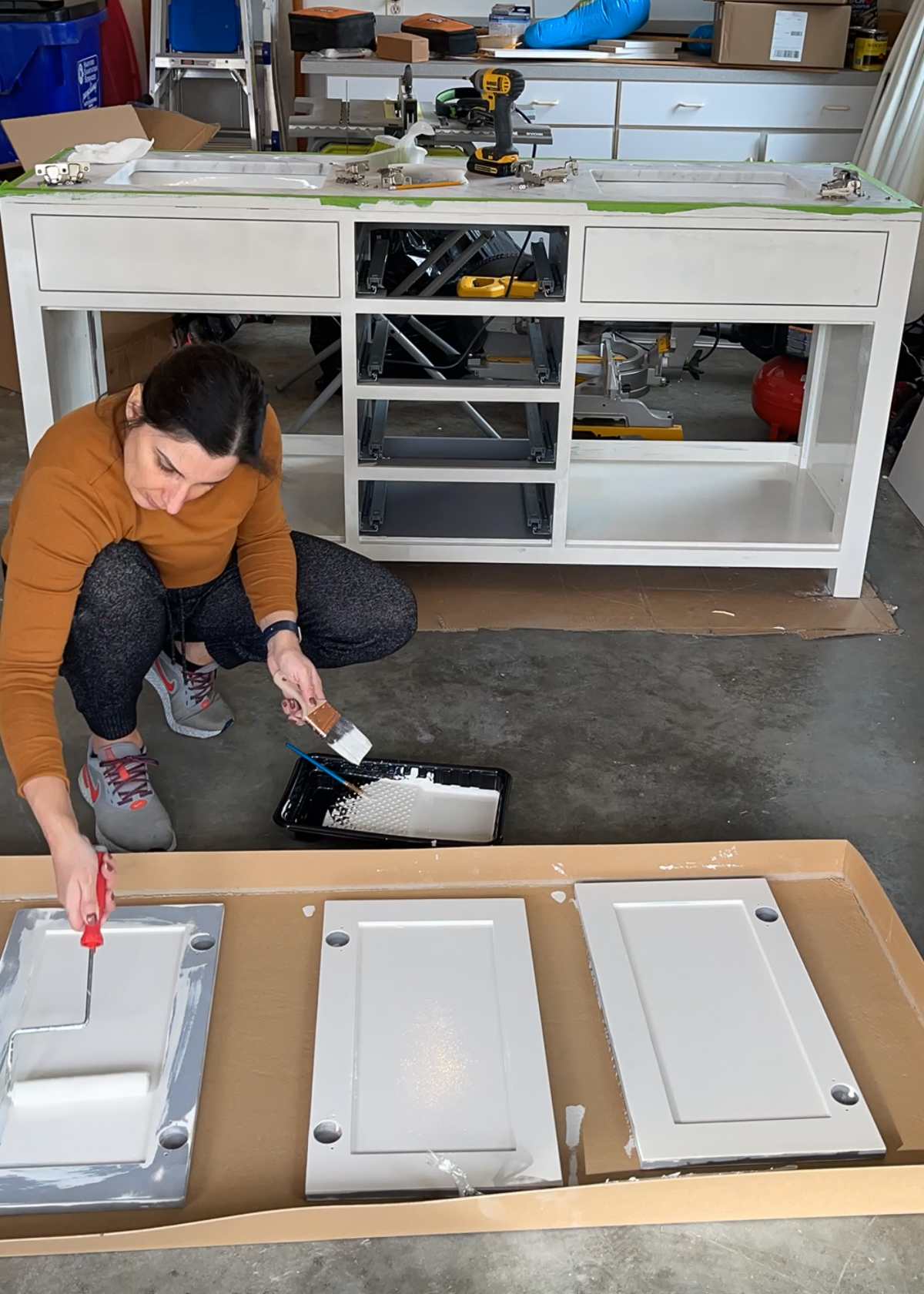 Stefana Silber painting vanity cabinet doors on garage floor using a mini roller