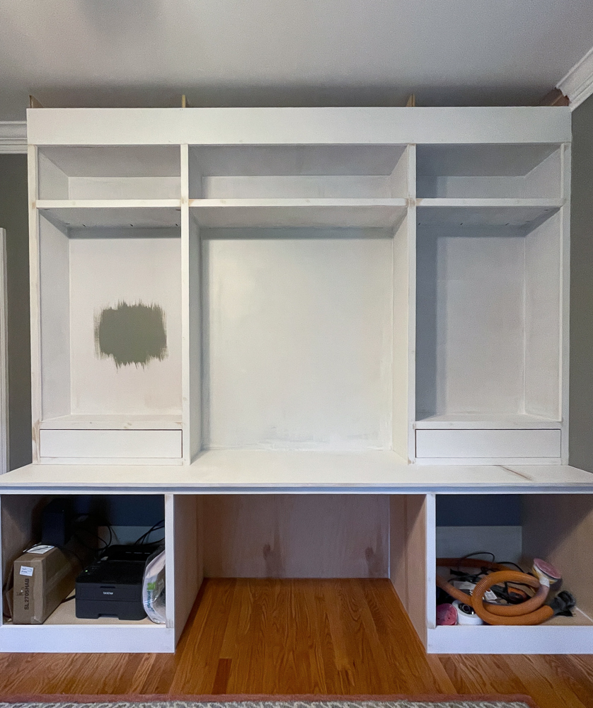 pull back view of construction of built in office cabinets with paint swatch on inside wall of cabinet