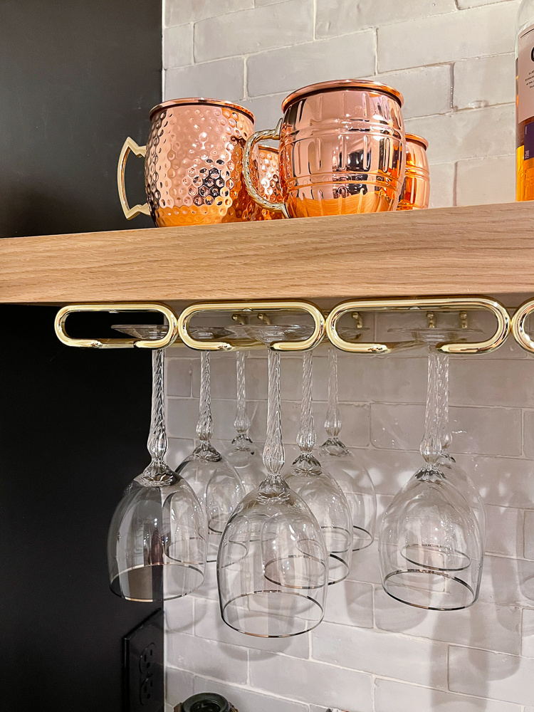 close up of wet bar open shelving, Moscow mule mugs on top of shelf, wine glass holder underneath shelf