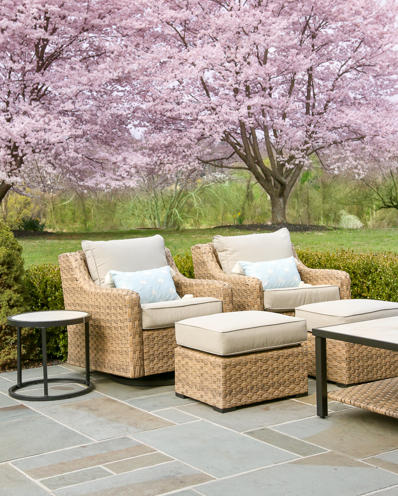 Walmart river oaks swivel chairs and ottomans paired with side tables on bluestone patio, cherry blossoms in background