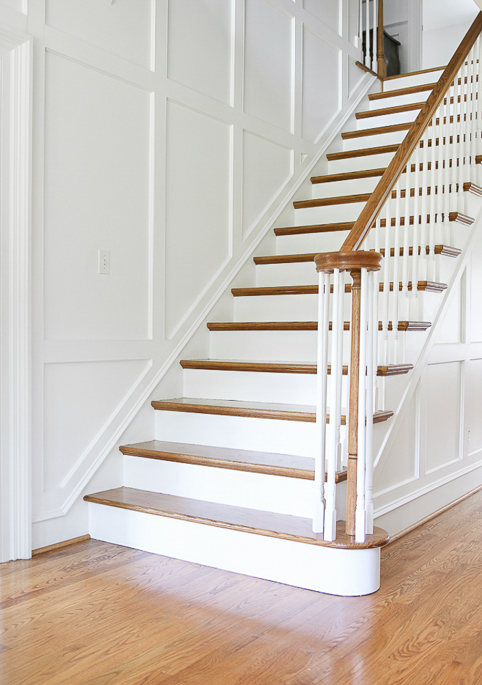 stairway with white walls with molding, wood floors, elegant and sophisticated home