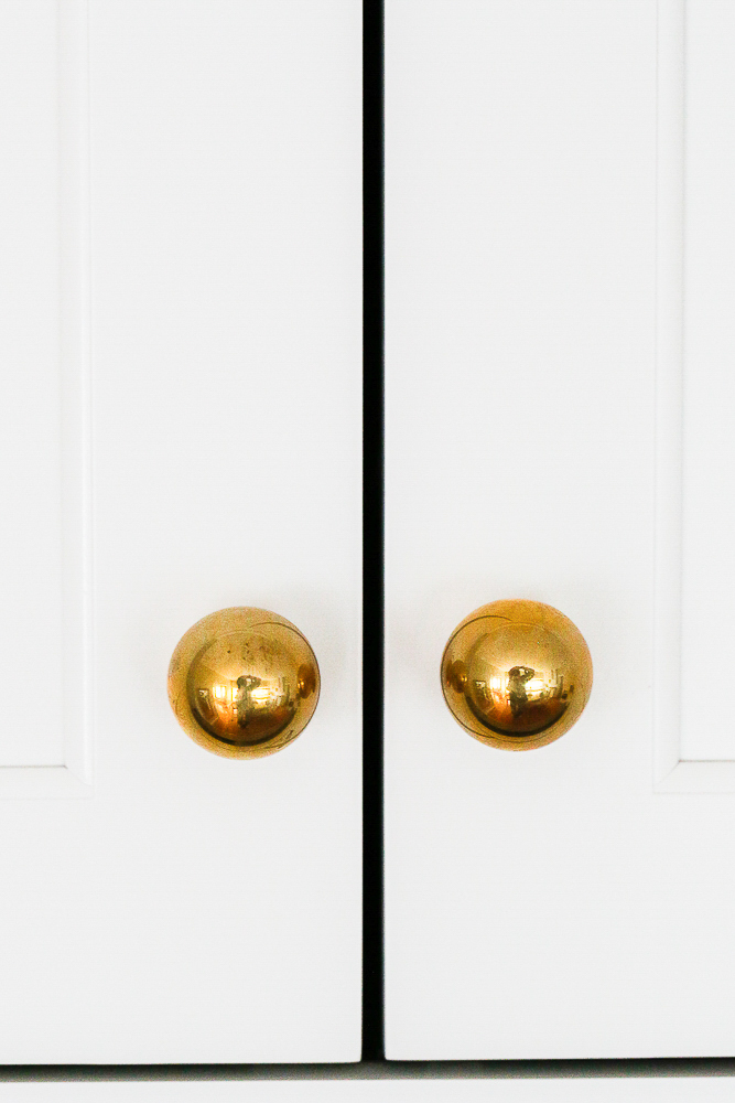 close up of unlacquered brass hardware with minimal tarnish, white cabinets