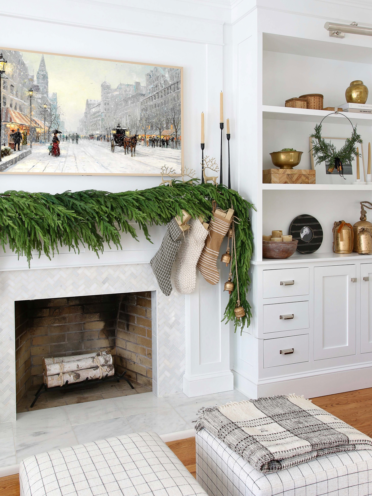 Fireplace mantel decorated with garland and stockings, frame tv above