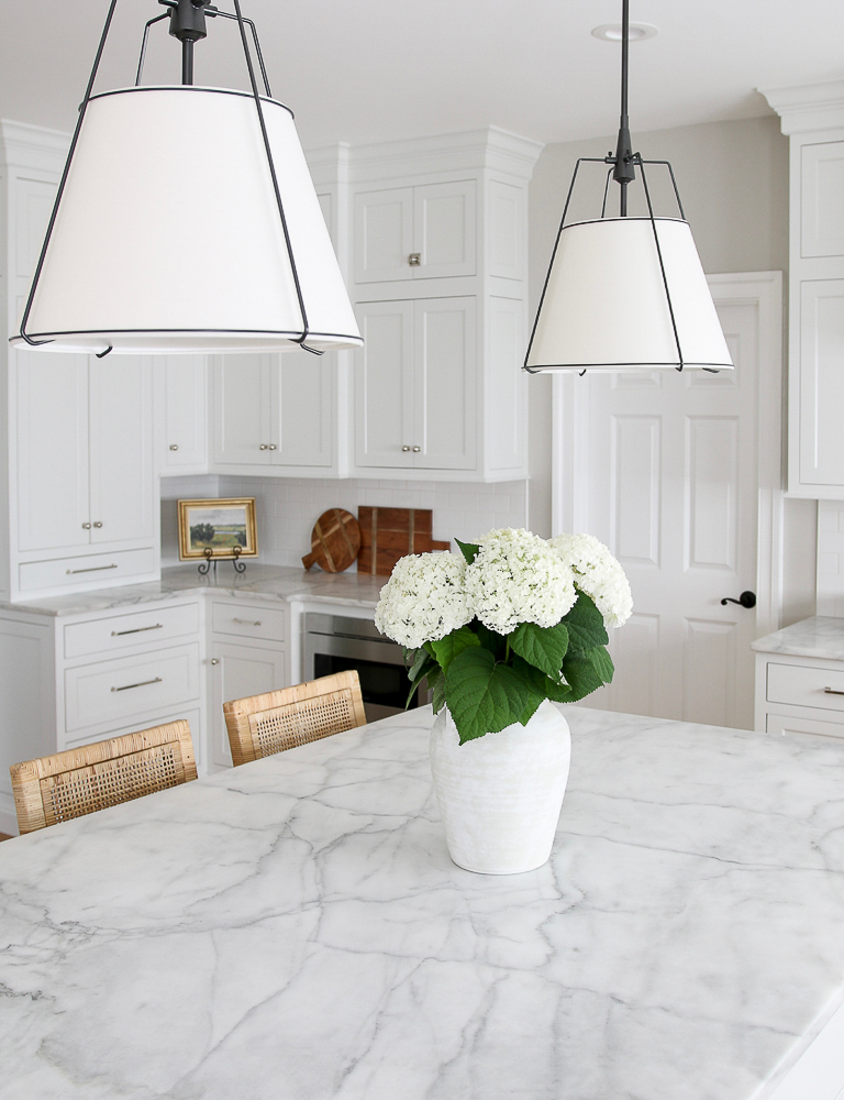 best lighting for a white kitchen, drum shade pendants with black accents, marble countertops, agreeable gray walls